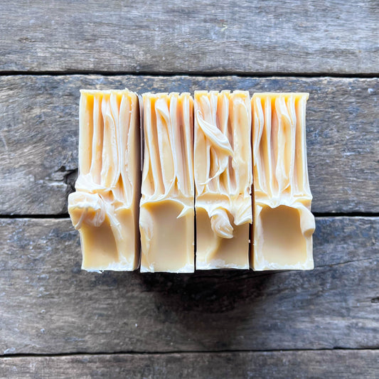 Three bars of soap cut from a larger block on a wooden surface
