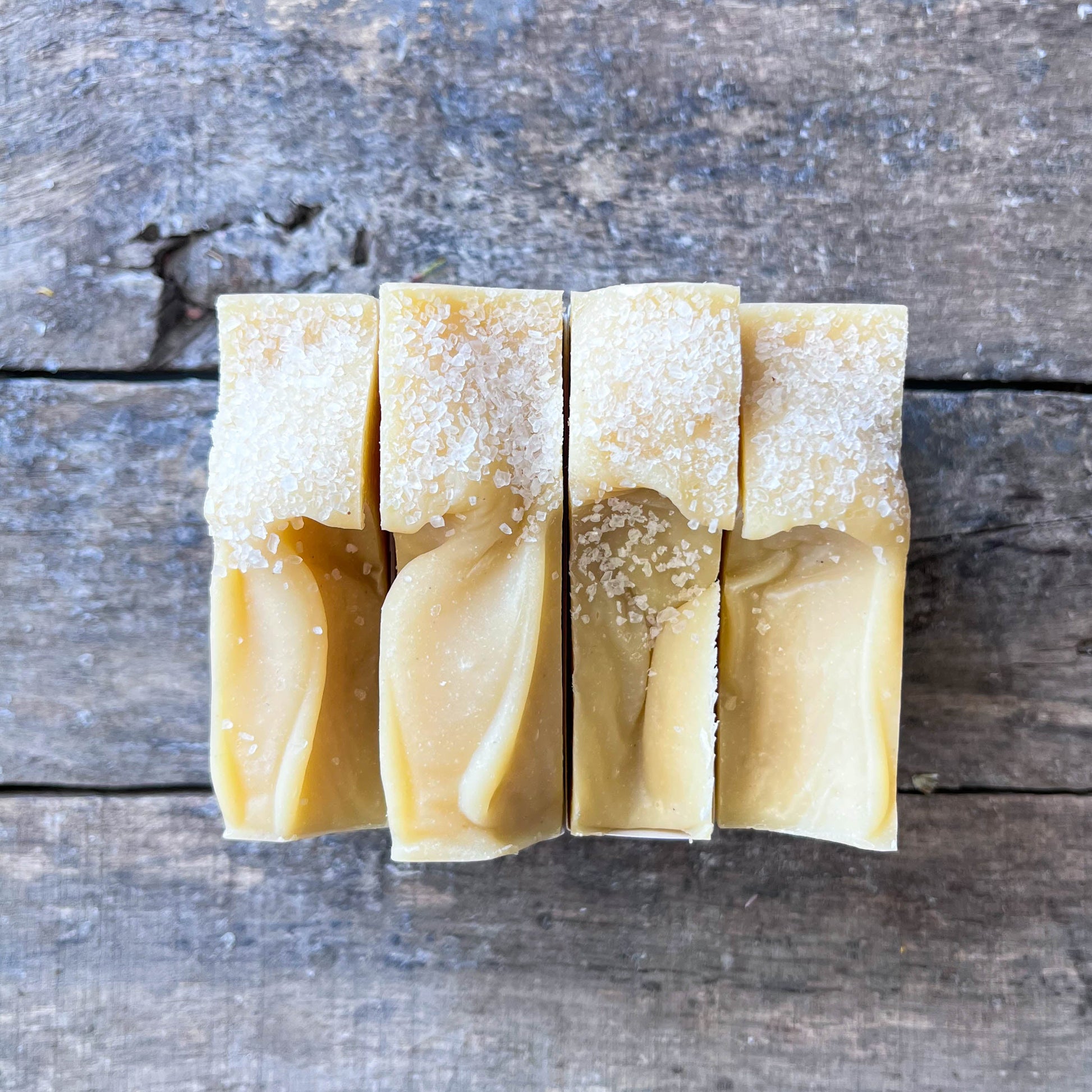 Five bars of soap stacked on a wooden surface