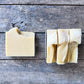 Bar of soap and a folded piece of soap on a wooden surface