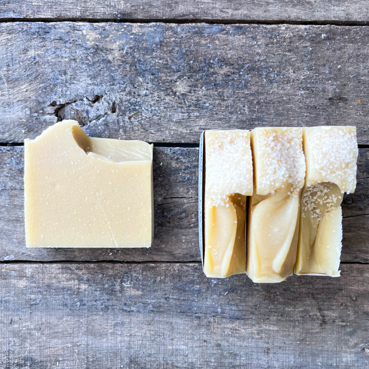 Bar of soap and a folded piece of soap on a wooden surface