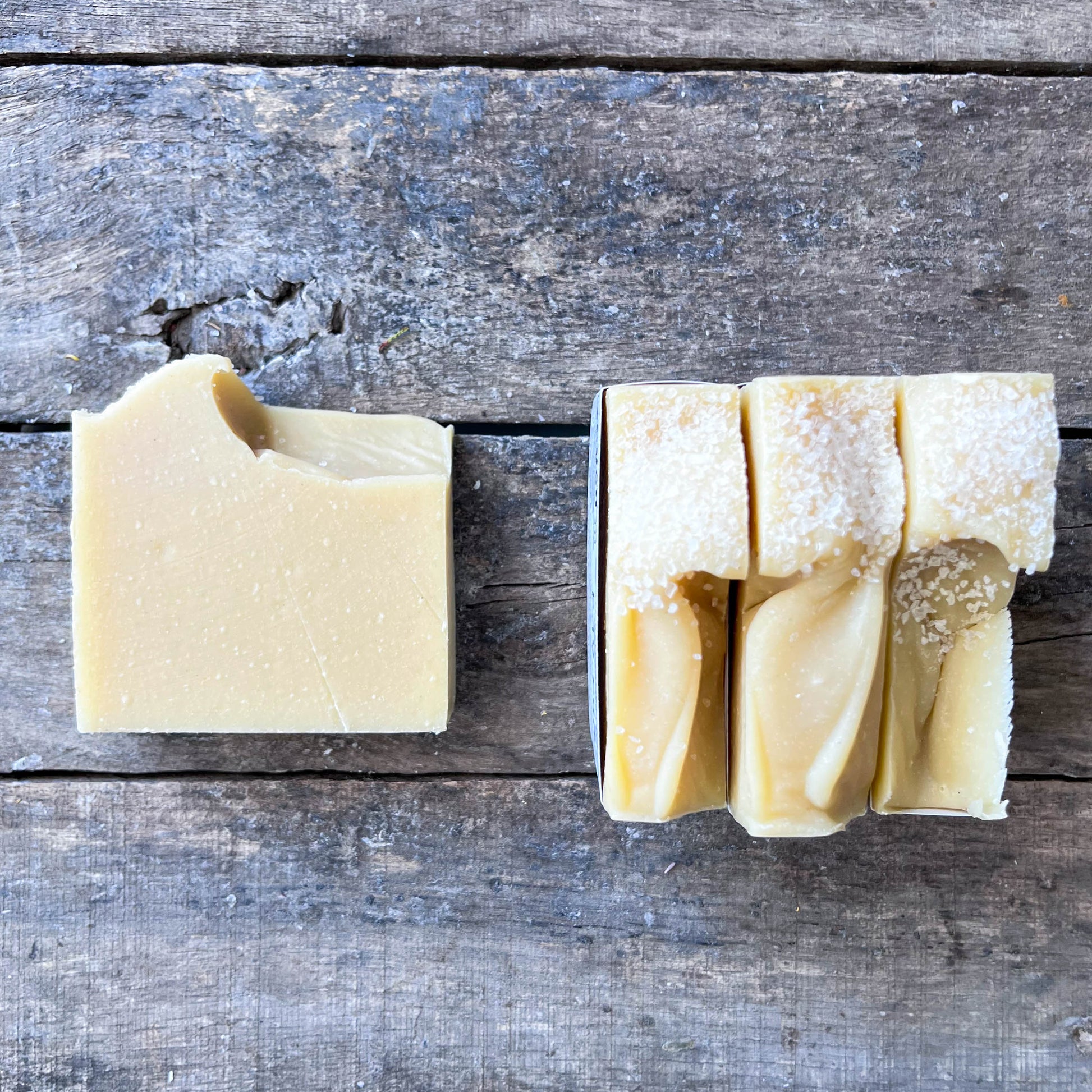 Bar of soap and a folded piece of soap on a wooden surface
