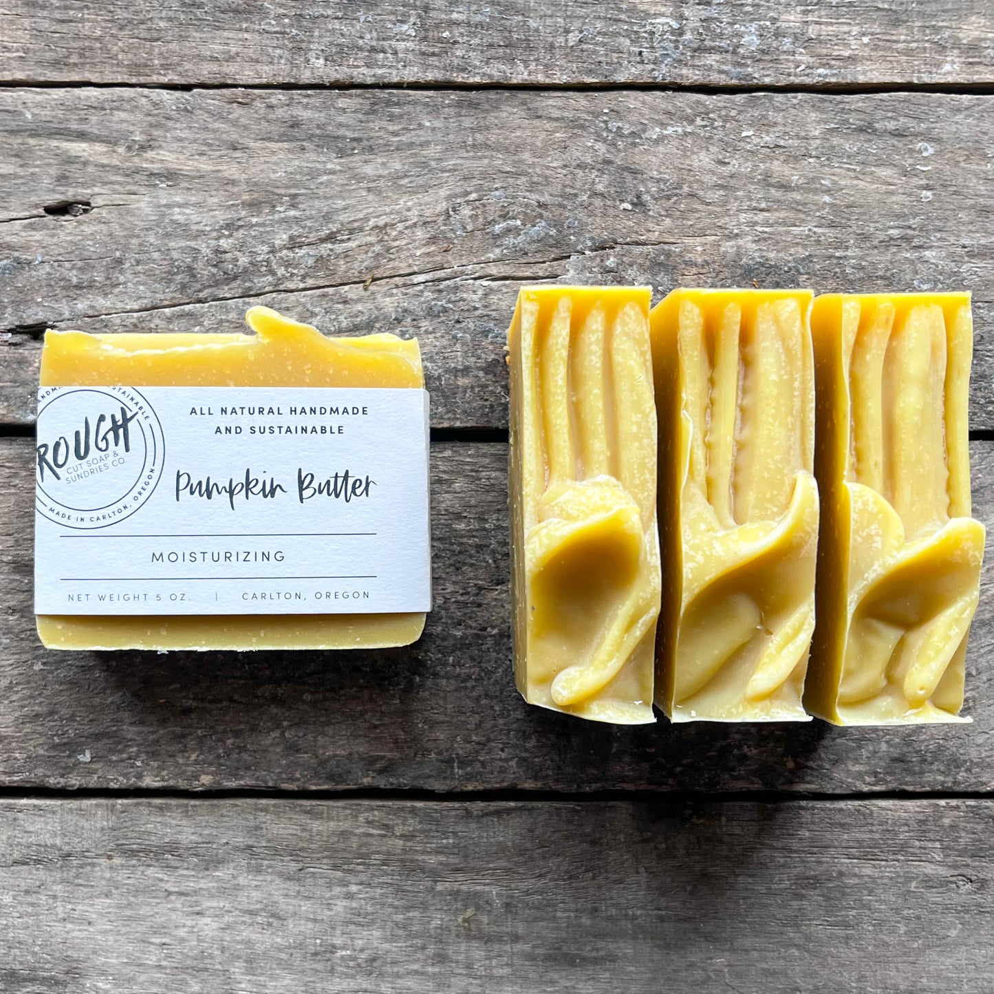 Three bars of yellow soap with a label on a wooden surface