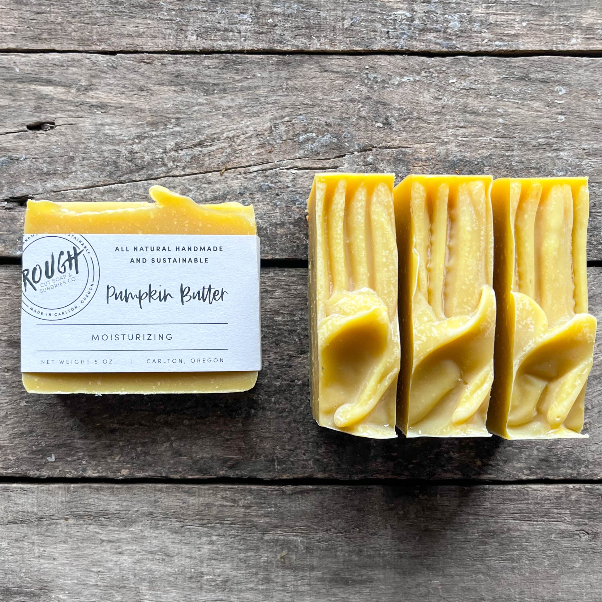 Three bars of yellow soap with a label on a wooden surface