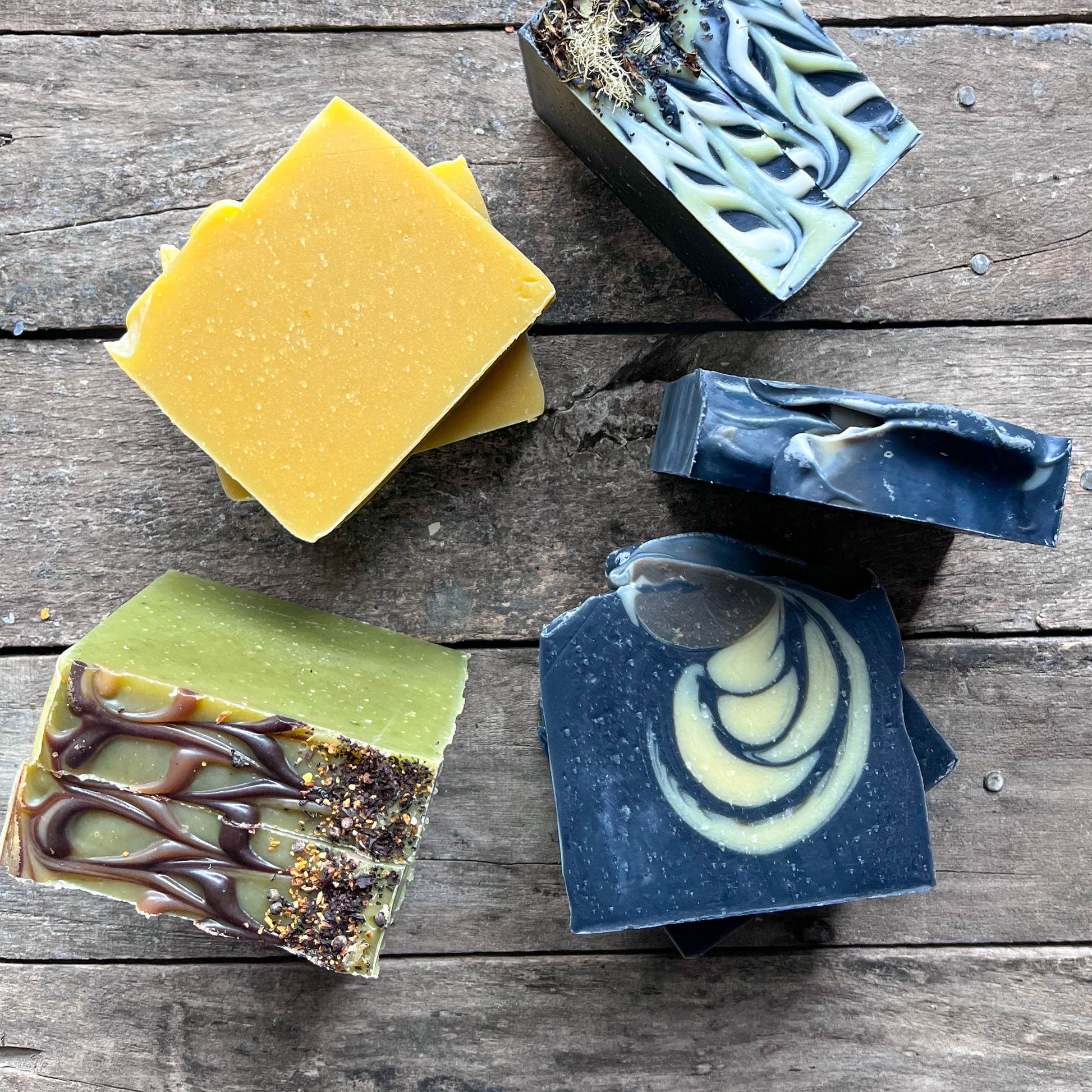 Five different bars of soap on a wooden surface