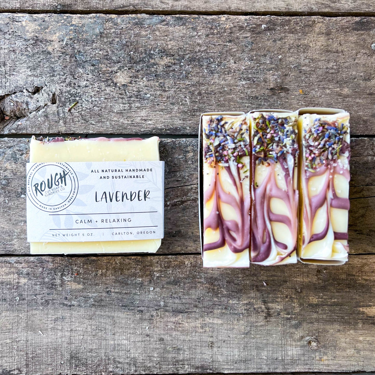 Three soap bars with lavender on a wooden surface