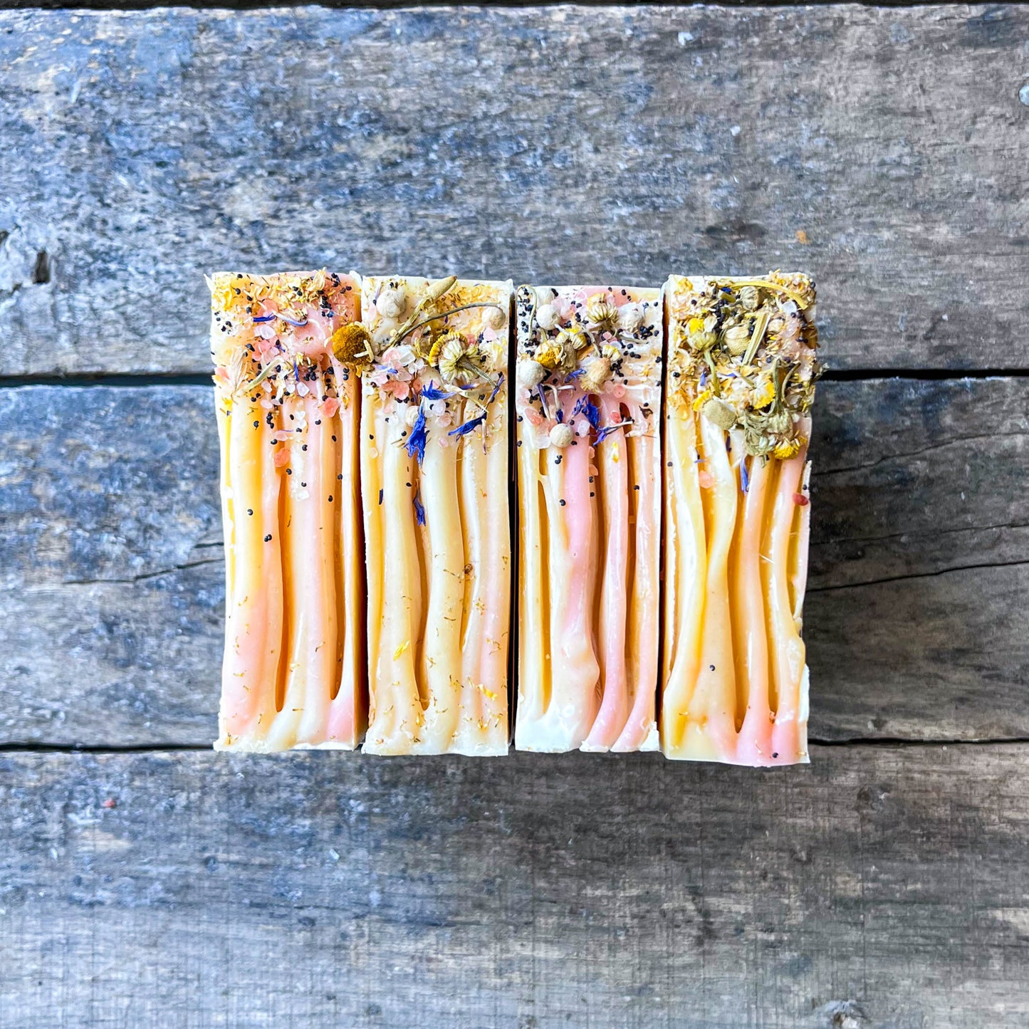 Five rectangular soap bars with different color patterns on a wooden surface