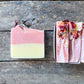 Two bars of soap with natural ingredients on a wooden surface
